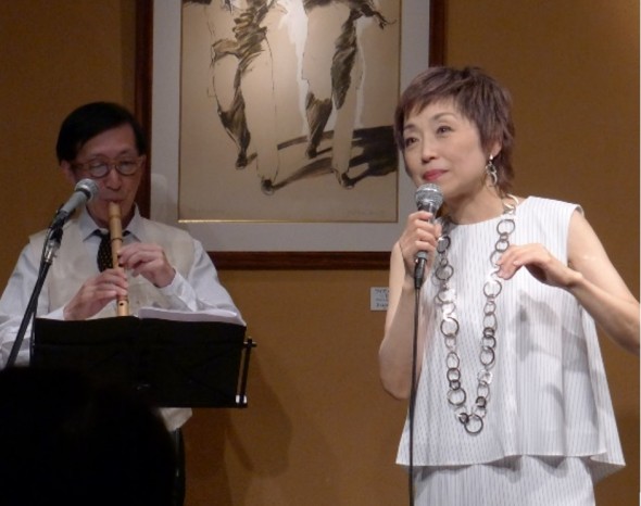 出版記念の集いで『広い河の岸辺』を歌うクミコさんと演奏する八木倫明さん(左)