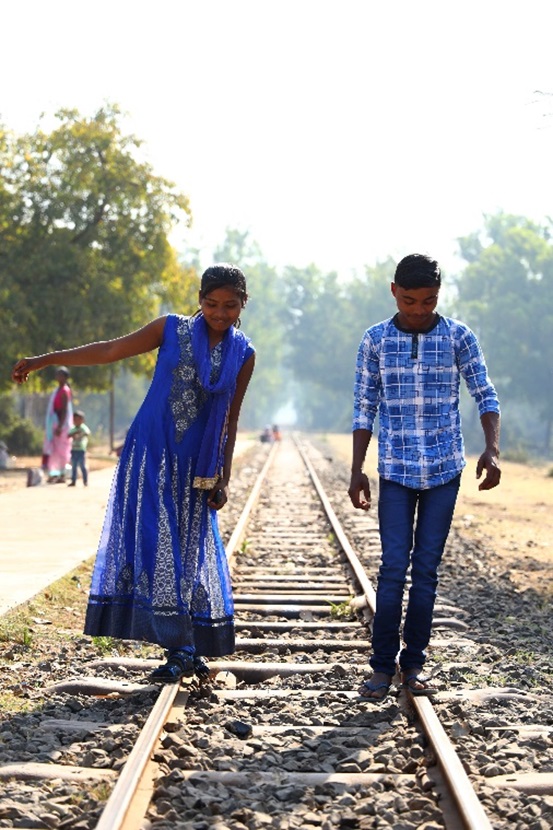 列車を待つ間に遊ぶ少年と少女。揃いの色の服で着飾った二人の関係は、想像するより他にない。70cm余りの線路の幅が、今の二人の精一杯の距離なのかもしれない。(2019年、インド グジャラート州にて)
